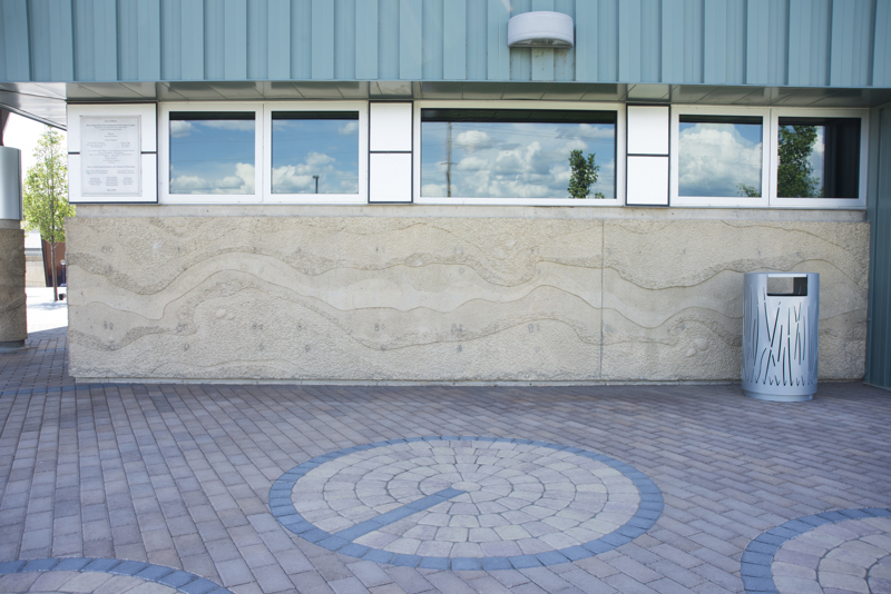 The exterior side of the Boise WaterShed building. Along the bottom four feet of the building is a cement textural installation that resembles a birds-eye view or map of a river and its previous shorelines that have shifted over time.
