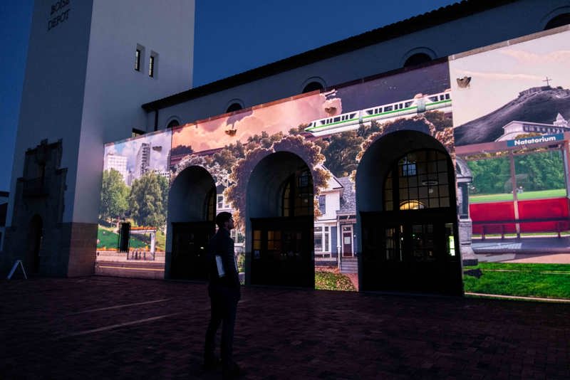 A photograph of the Boise Depot at sunset. On the front of the building is a bright animated projection.