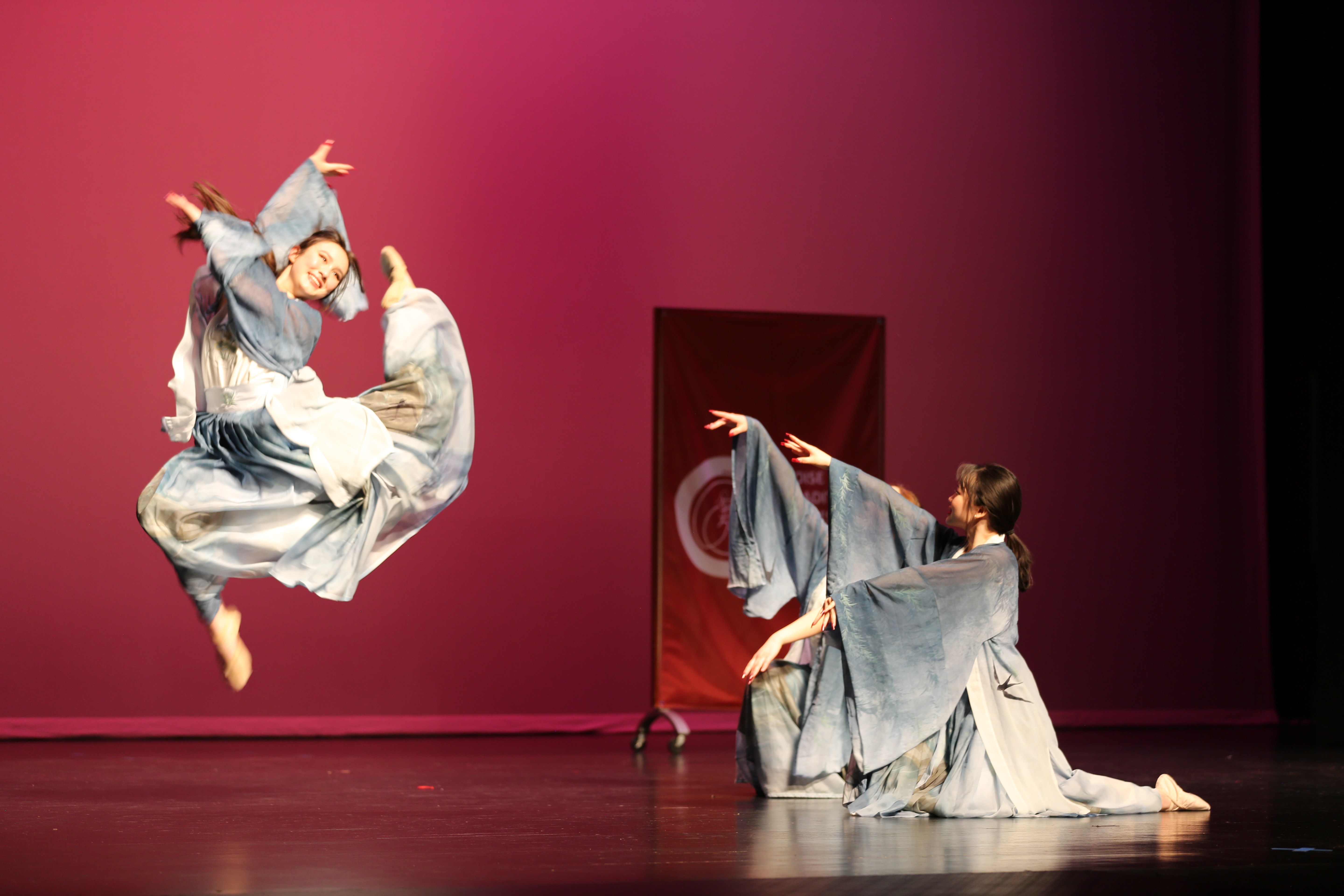 Two dancers with Chinese traditional costumes on dancing on a stage.