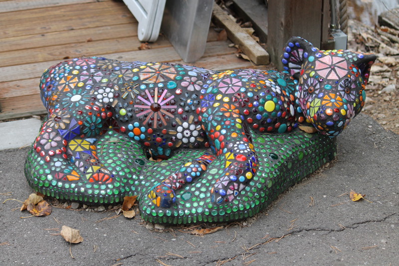A glass mosaic sculpture of a hyena laying on the ground.