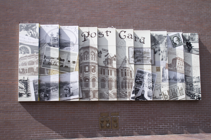 An installation of 10 rectangular layers overlapping one another like fallen dominoes. The surface of one side depicts a collection of photos a postcards of or from Boise. The other thinner edge depicts a single vintage postcard with the prominent text "BOISE". This give the illusion of seeing two different images from two different angles.