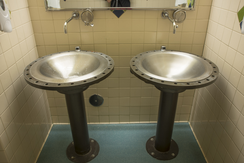 Two bathroom sinks made from large metal water main pipes and hardware.