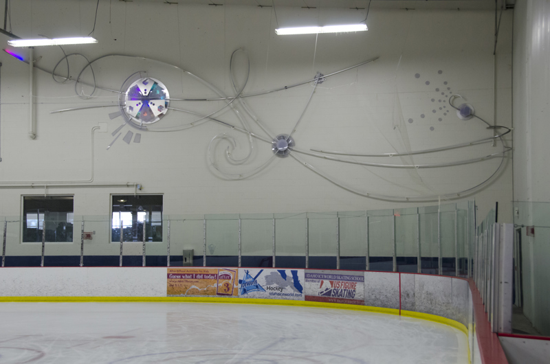 And abstract wall and light installation of curved metal strips and discs lined with color changing LED lights.