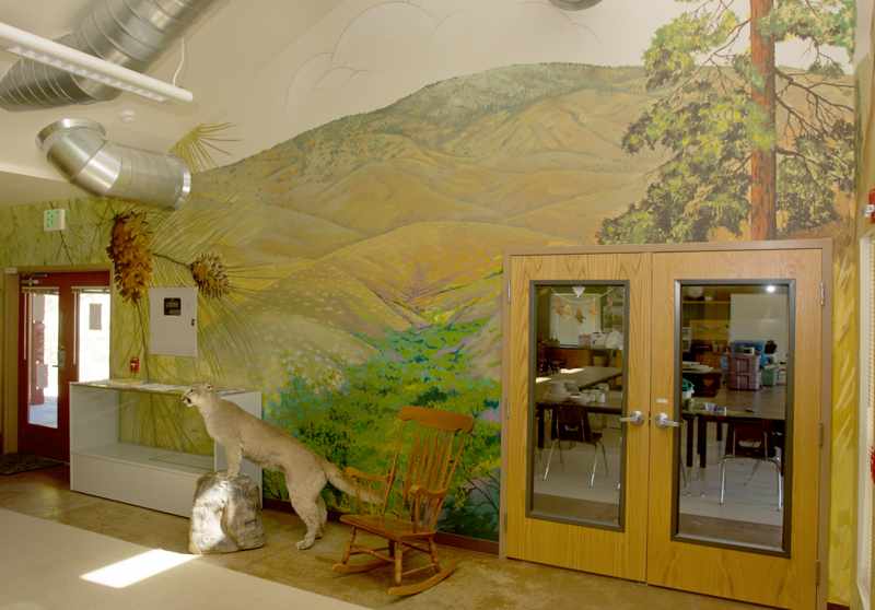 The main office of the Boise Foothills Learning Center. On the walls is painted a mural depicting the Boise Foothills with ponderosa trees and ground brush.