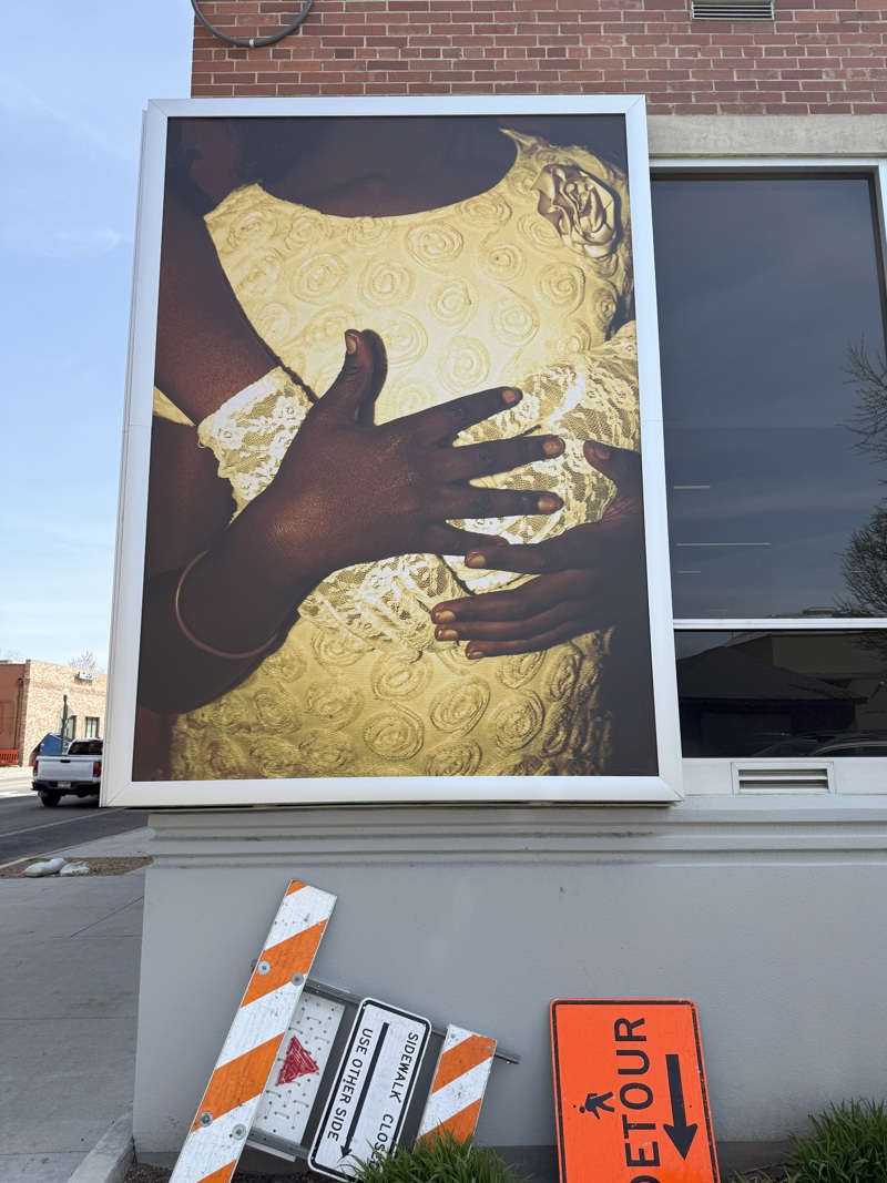 A photograph of black hands wrapping around a torso wearing a white dress.