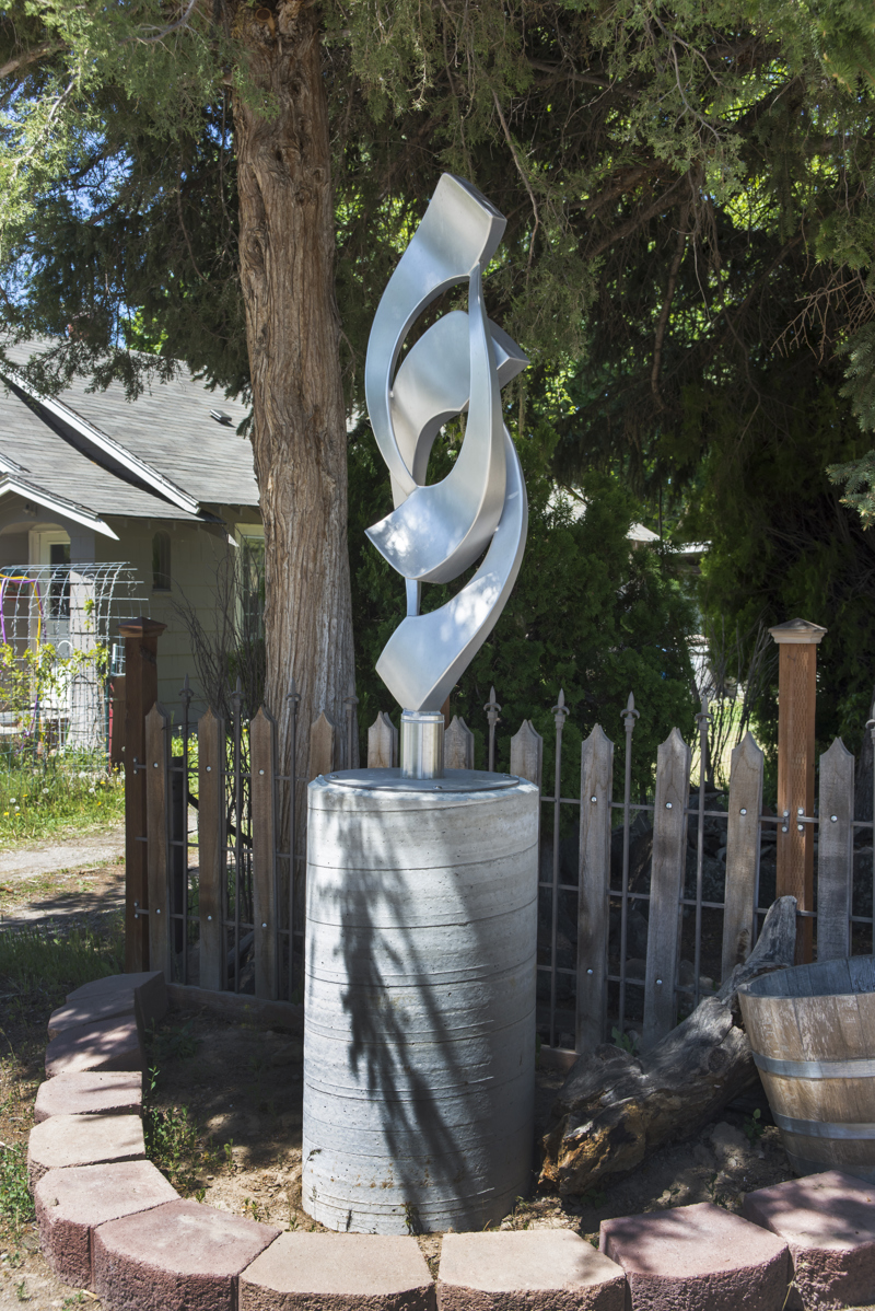 A medium abstract stainless steel sculpture on a concrete column. 