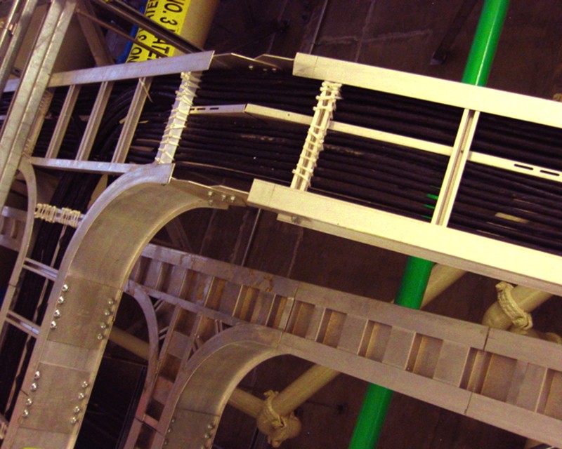 A number of black tube pipes organized and held within a silver metal support armature. 