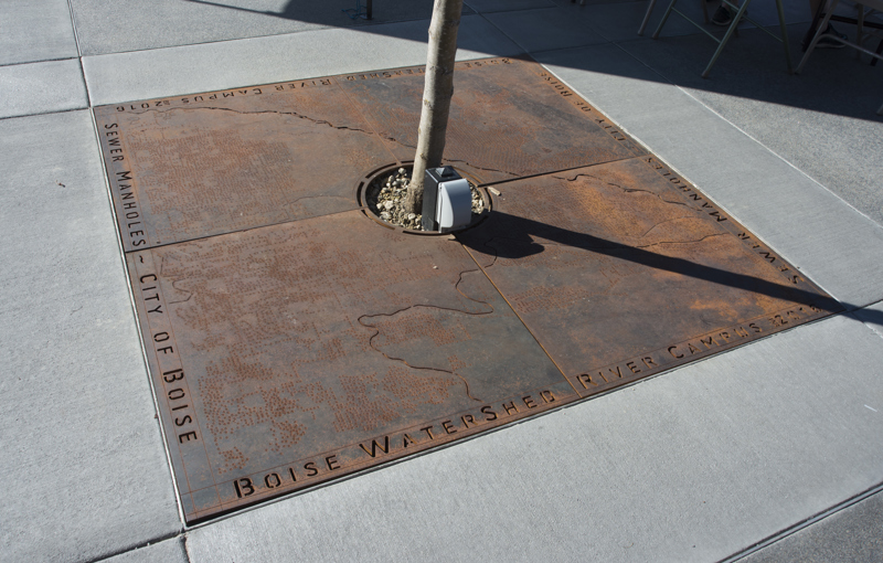 A steel tree grate cut to depict a map locating all the sewer manhole covers in Boise.
