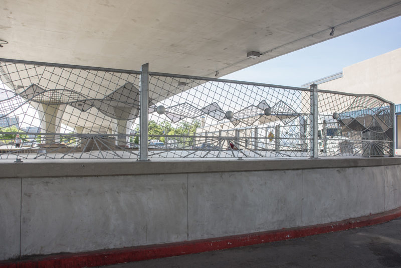 A decorative galvanized steel fence at the far end of a skate park.