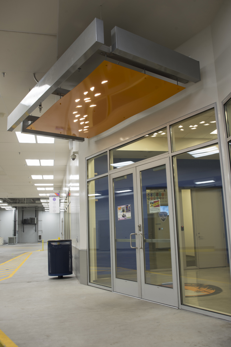 A doorway awning made of painted cut metal. In the awning, lit with backlighting, are holes in the shape of butterflies.
