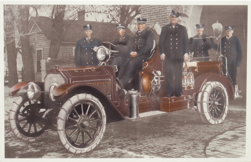 An image of firefighters standing next to a fire car in 1915.