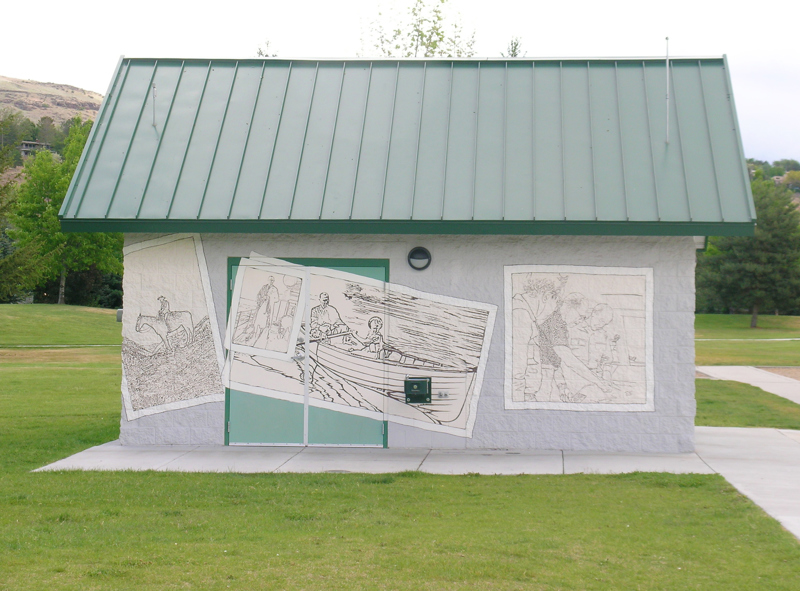 A park restroom shelter made of cinderblock. Painted on the outside is a mural depicting several photographs.