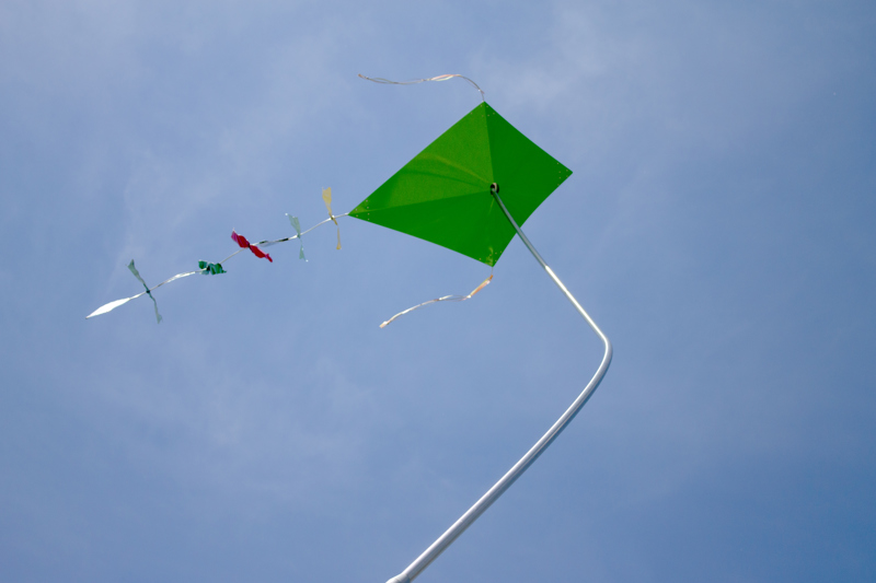 A closeup of one of the kites which green and in the traditional diamond shape.