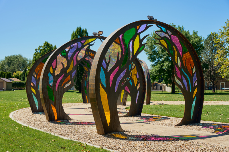 Series of six steel archways with cut tree patterns and colorful acrylic panels covering the voids.