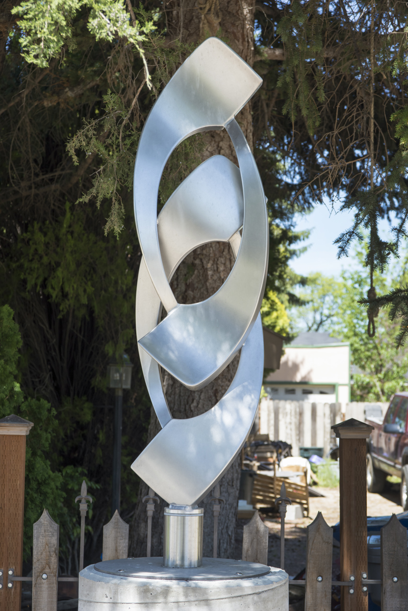 A medium abstract stainless steel sculpture on a concrete column. 