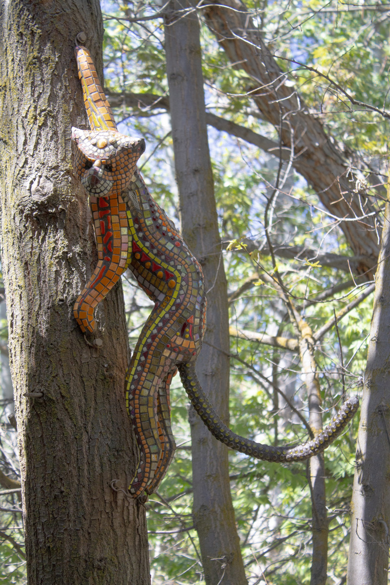 A glass mosaic sculpture of a monkey attached to a tree.