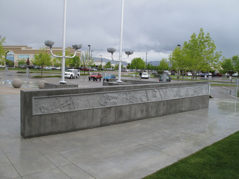 A concrete wall with a low-bas relief sculpture of various first responders in action and their equipment throughout Boise's history.