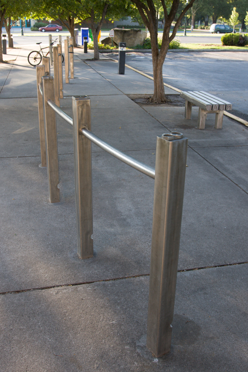 A stainless steel bicycle rack made with posts that look like letter blocks used in old printing presses.