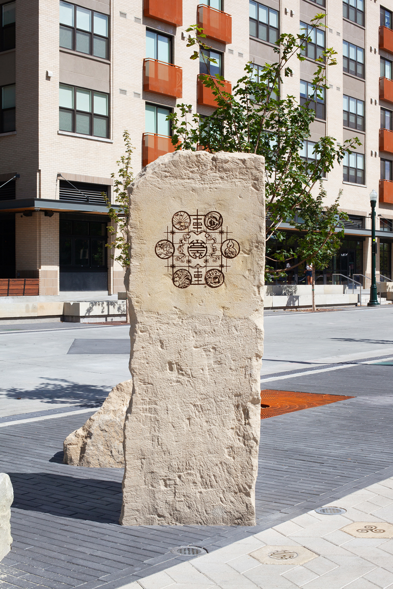 A sandstone pillar with an etching of Chinese motifs and symbols.