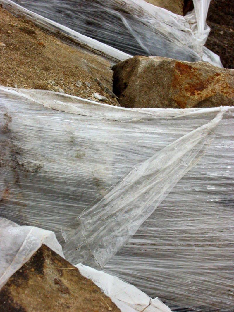 A number of large sandstone rocks wrapped in plastic.
