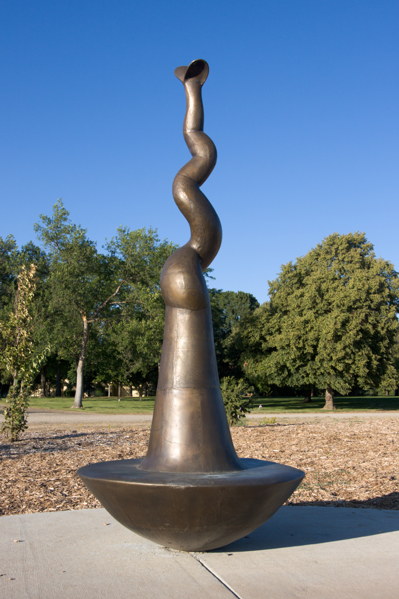 A large bronze circular bench with a center that rises in the shape of a sprout.