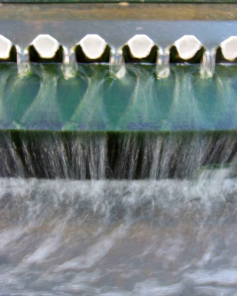 Water pouring through a toothed grate meant to separate out unwanted materials.