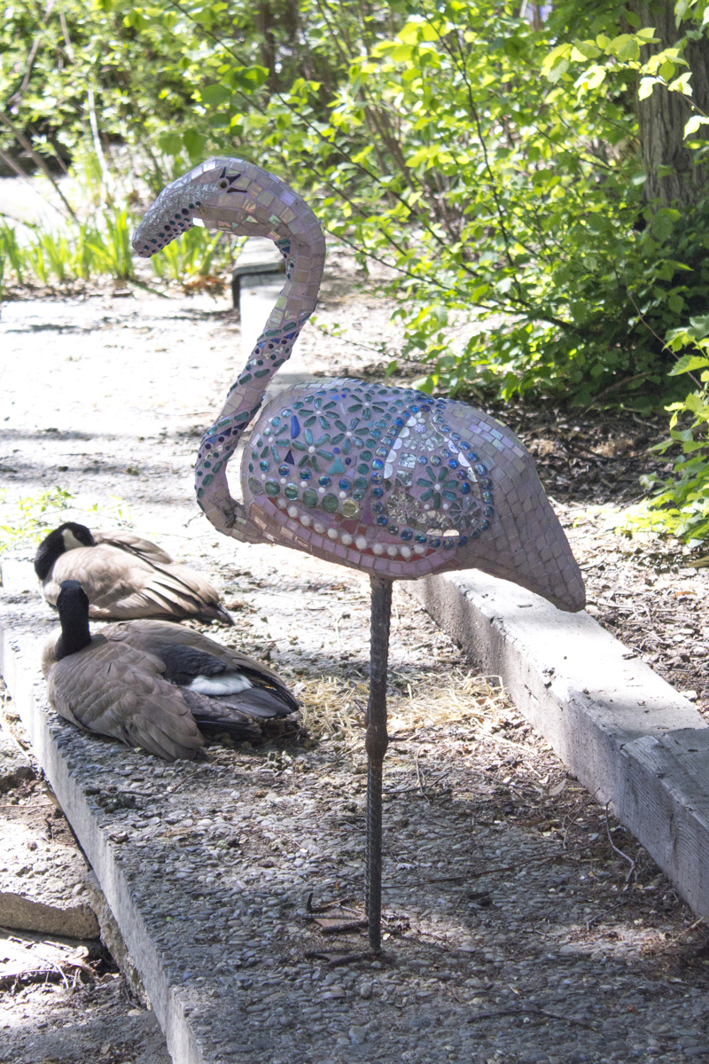 A glass mosaic sculpture of a flamingo standing on both legs.
